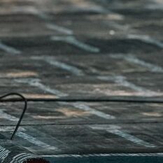 A construction worker applying a waterproofing coat on a rooftop with a roller during daytime.